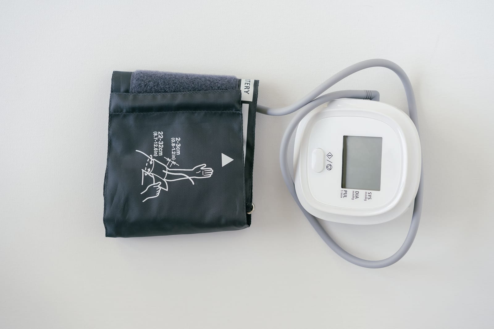A close-up of a digital blood pressure monitor with its display and cuff