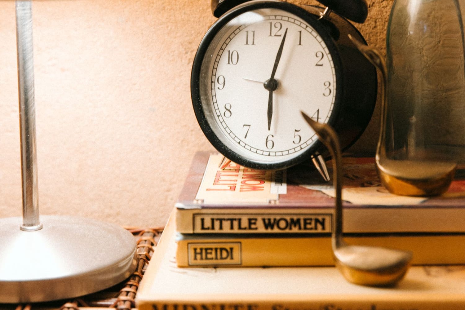 A softly lit bedside table at night with a vintage alarm clock and a glowing lamp, the scene of a middle-of-the-night waking