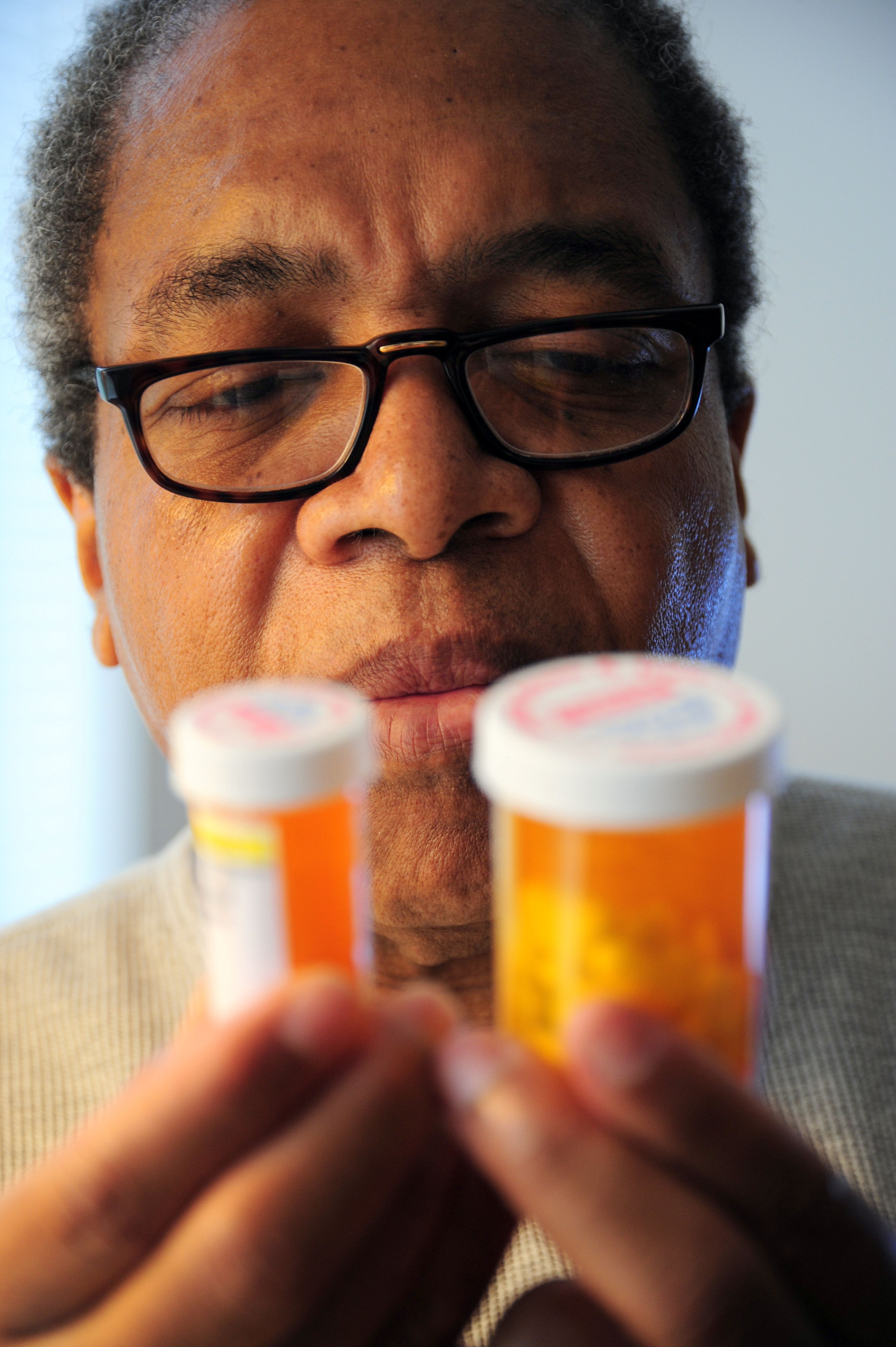 A senior adult man examining his prescription blood pressure medication bottles at home