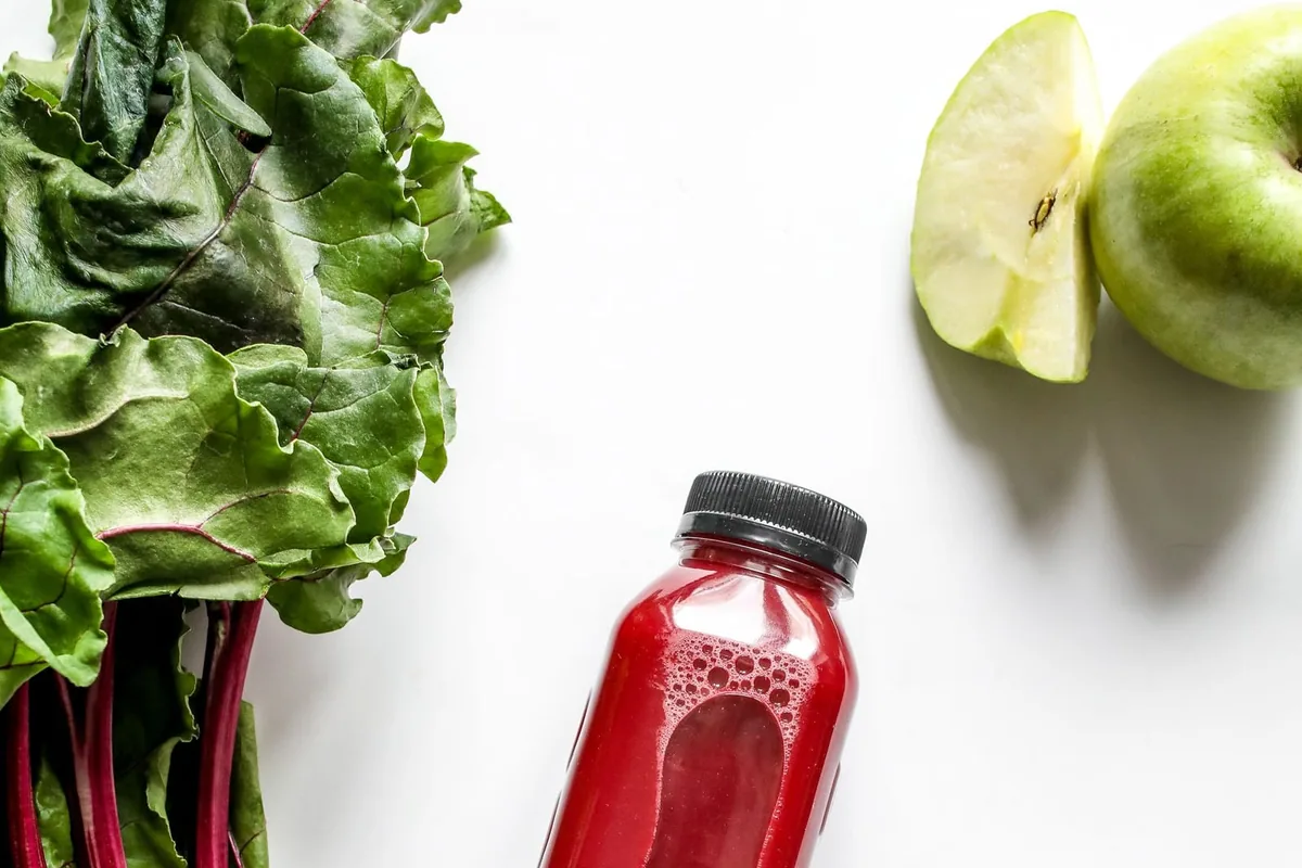 Fresh beetroot, apple, and cucumber beside a bottle of beetroot juice, representing the ingredients with real research behind blood pressure support