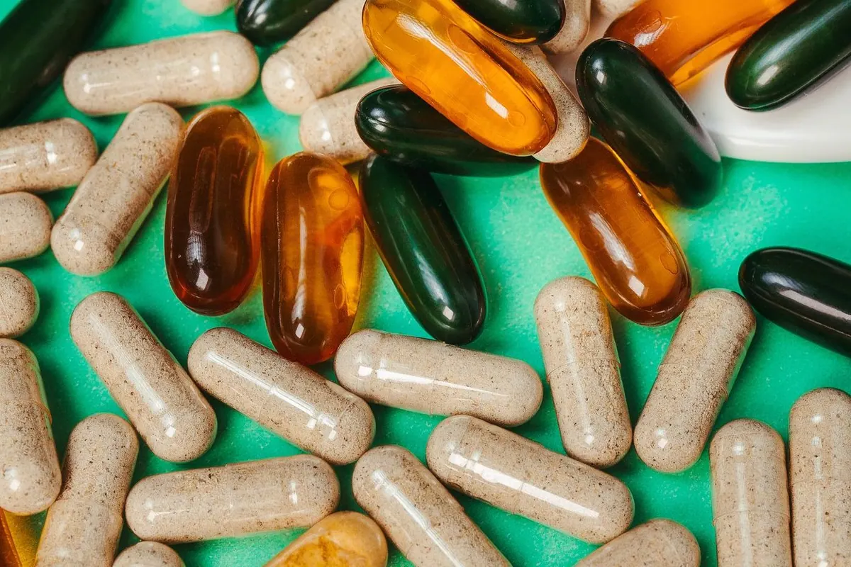 A close up of assorted supplement capsules and tablets on a light background
