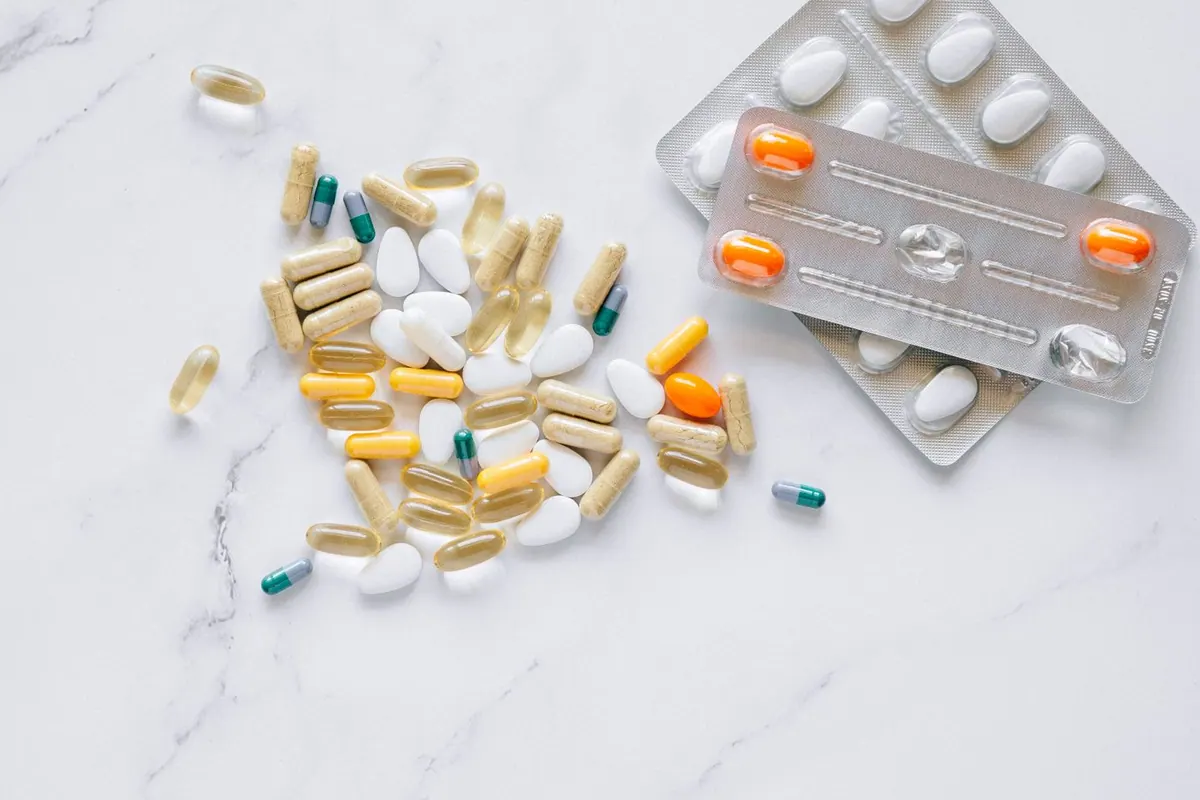 An assortment of supplement capsules photographed close up on a pale surface