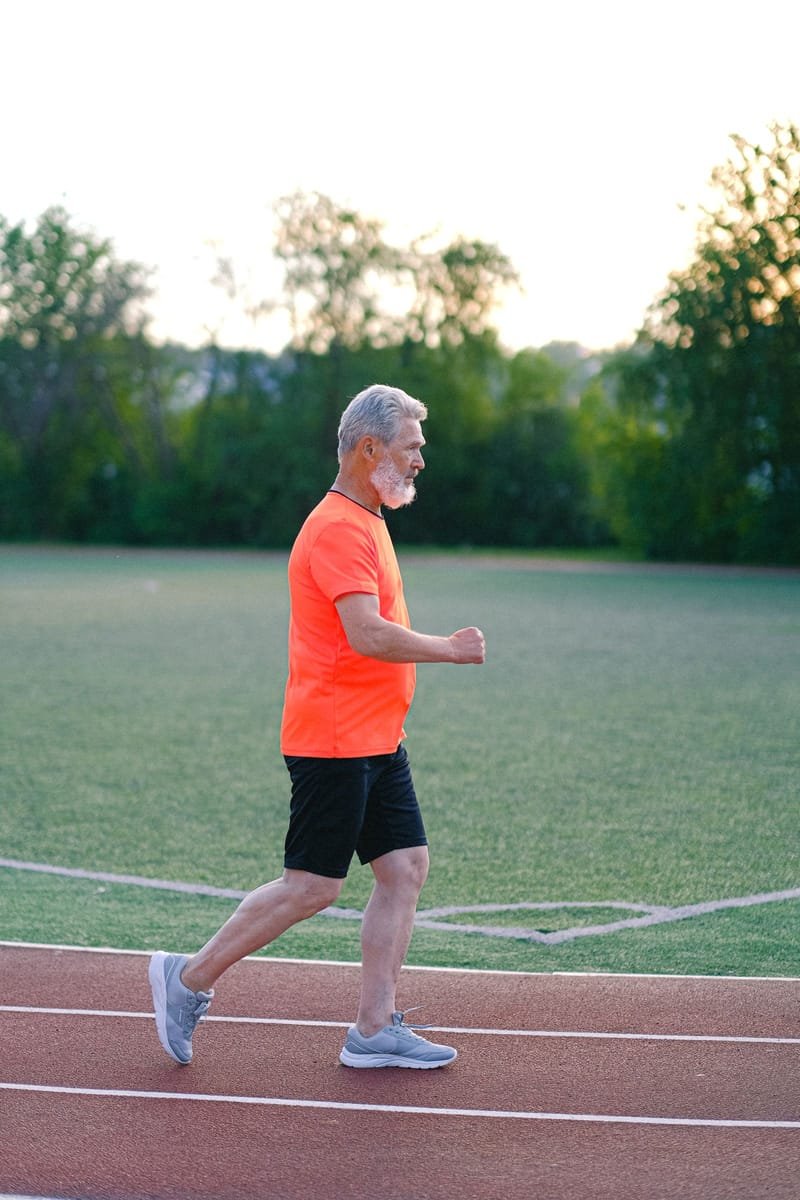 A senior man jogging on an outdoor track as part of a healthy, active lifestyle