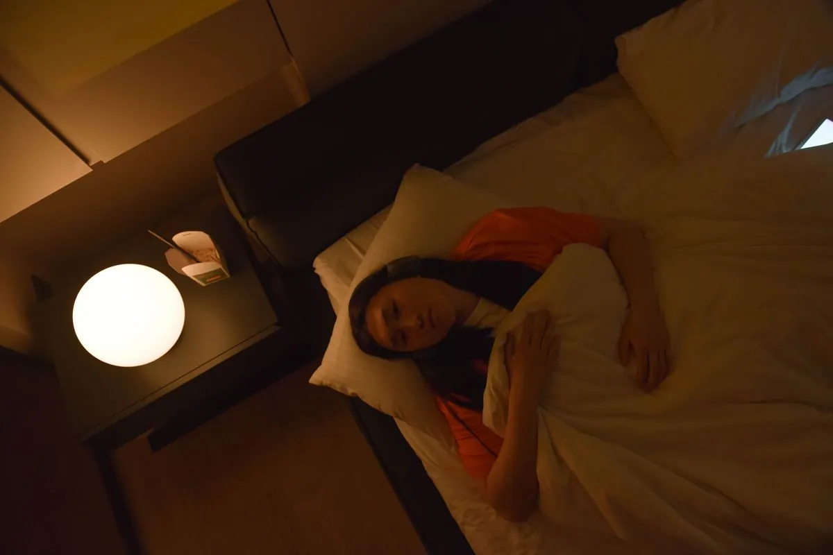 A woman lying awake in a dimly lit bedroom at night