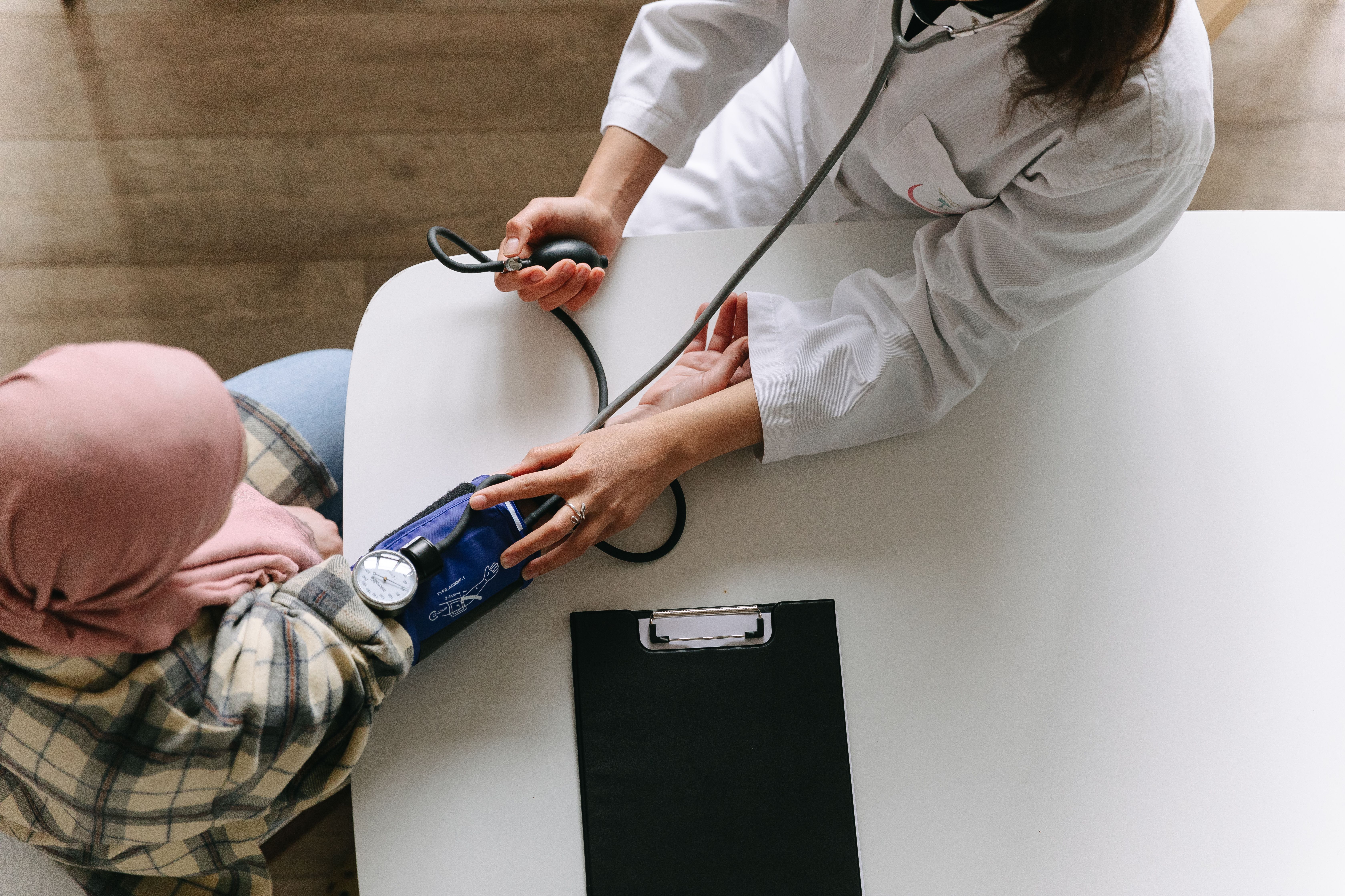 A doctor checking a patient's blood pressure with a manual cuff during a consultation about medication options
