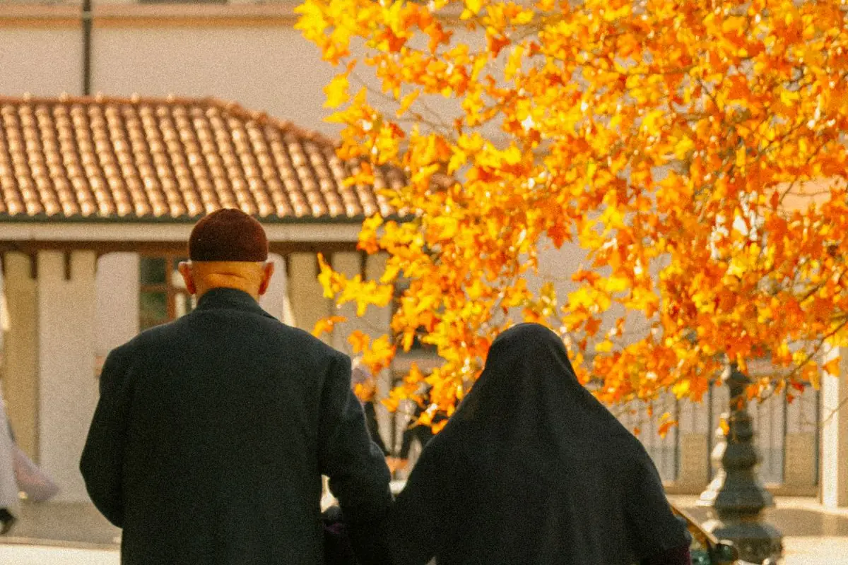 An older couple walking together outdoors on a tree-lined path, one of the lifestyle habits that can help lower blood pressure without medication