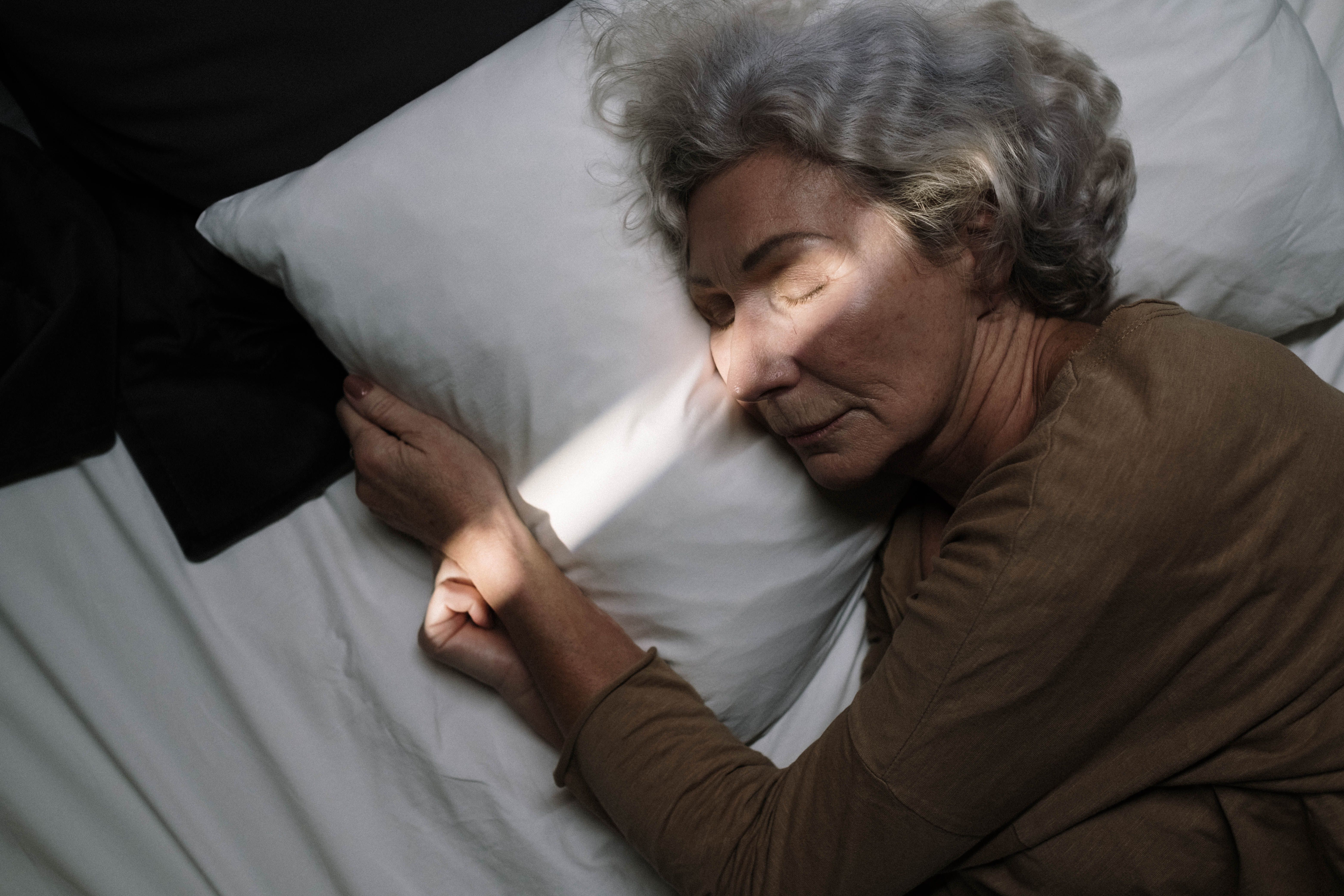 Older woman asleep at night, illustrating nocturnal hypertension, high blood pressure at night that goes unnoticed during sleep