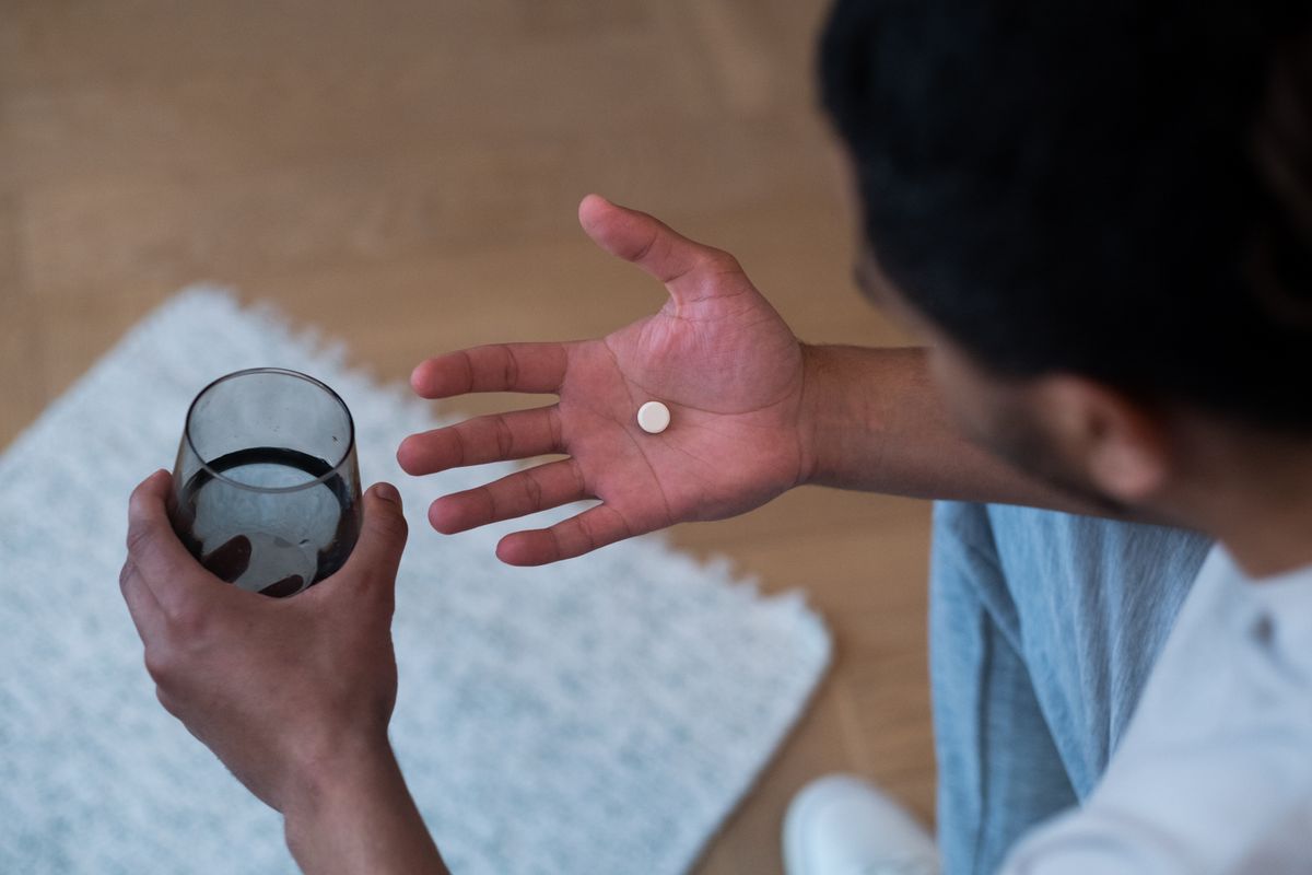 A man holding a glass of water and a pill at bedtime