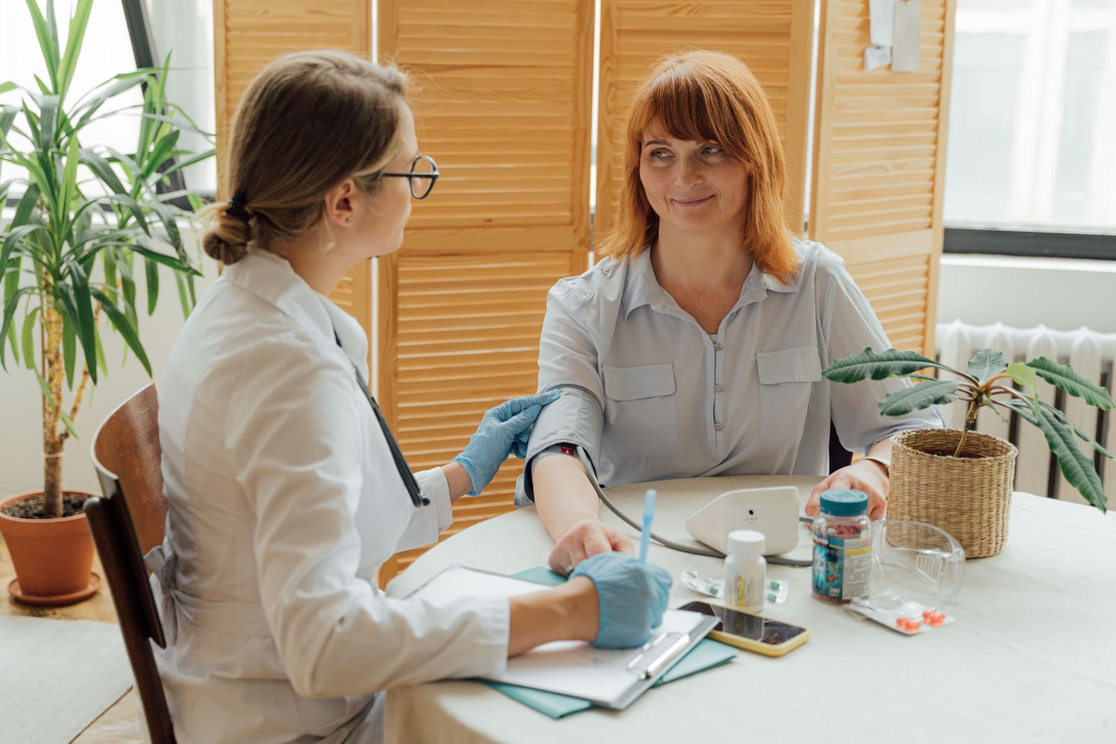 A healthcare provider checking a patient's blood pressure during an office visit, representing the difference between clinical and home readings